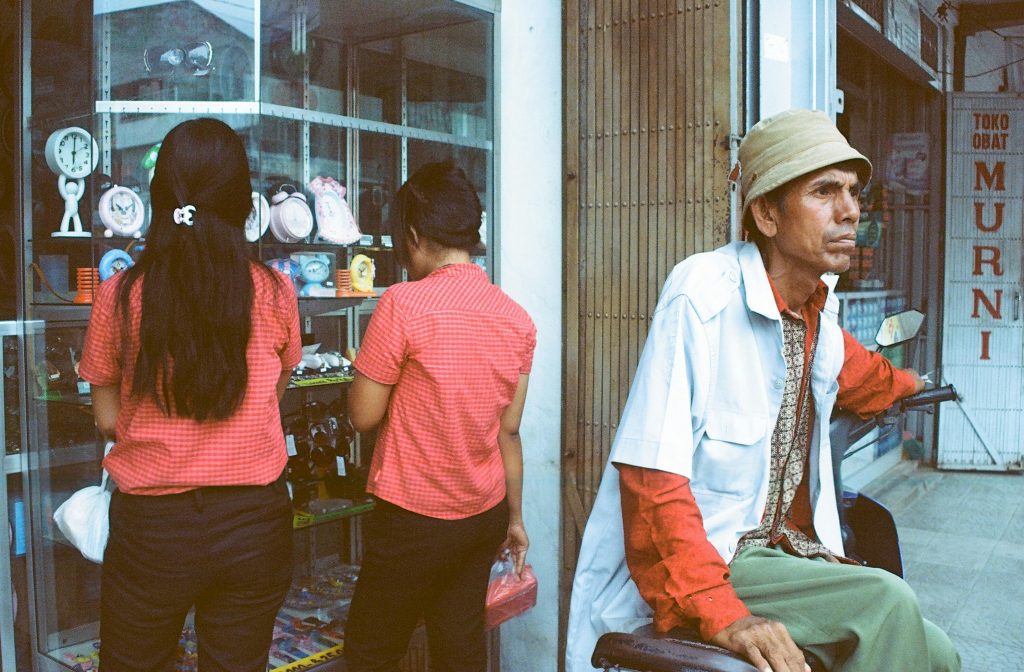 Man sitting in front of a traditional drugstore in Indonesia